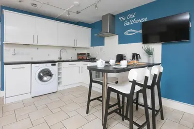 a kitchen with a black table and white cabinets at The Old Salthouse in St Ives