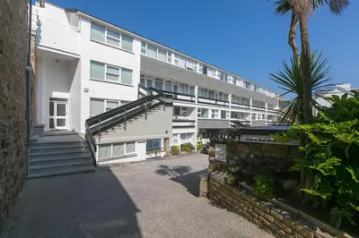 a large white building with stairs and a palm tree at The Old Salthouse in St Ives