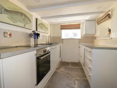 a small kitchen with white cabinets and a sink at Willow View in Wadebridge