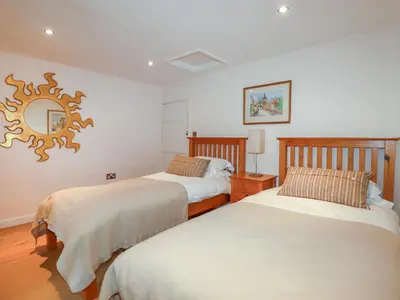 a bedroom with two beds and a mirror on the wall at Willow View in Wadebridge