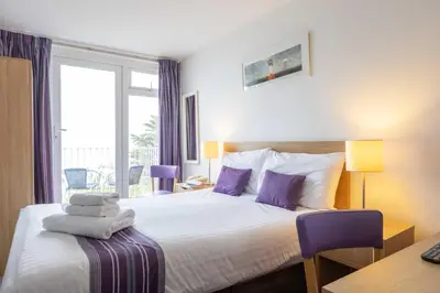 a hotel room with a bed with purple pillows at The St Ives Bay Hotel in St Ives