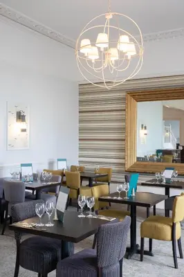 a dining room with tables and chairs and a chandelier at The St Ives Bay Hotel in St Ives