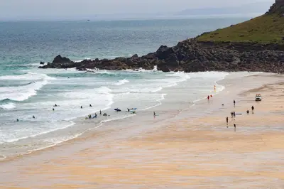 a group of people on a beach near the ocean at The St Ives Bay Hotel in St Ives