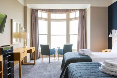 a hotel room with two beds and a desk and a window at The St Ives Bay Hotel in St Ives
