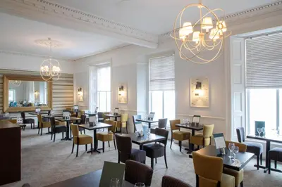 a restaurant with tables and chairs and a chandelier at The St Ives Bay Hotel in St Ives