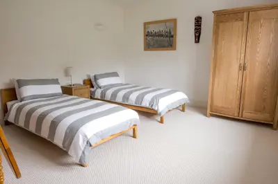 a bedroom with two beds and a wooden cabinet at Ocean View, 5 bedrooms sleeps 10, stunning views, parking x4 in Mevagissey