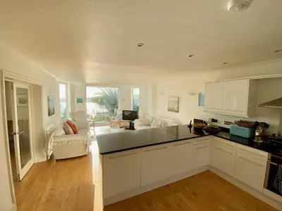 a kitchen with white cabinets and a living room at Ocean View, 5 bedrooms sleeps 10, stunning views, parking x4 in Mevagissey