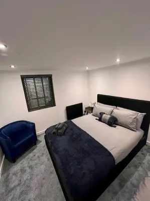 a bedroom with a large bed and a blue chair at The Middleton Beach Lodge in Looe