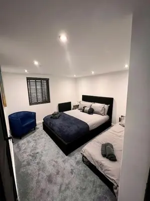 a bedroom with two beds and a blue chair at The Middleton Beach Lodge in Looe