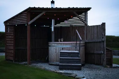 a wooden building with a hot tub in a yard at Great Tregath by Wigwam Holidays in Camelford