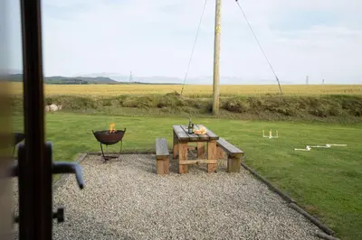 a grill and a picnic table in a field at Great Tregath by Wigwam Holidays in Camelford