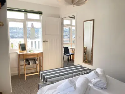 a bedroom with two beds and a desk and a mirror at 1 Sunnyside - views over the St Ives Harbour in St Ives