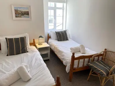 a bedroom with two twin beds and a chair at 1 Sunnyside - views over the St Ives Harbour in St Ives
