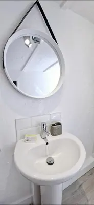 a white sink with a round mirror above it at Cottage in Newquay