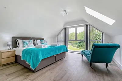 a bedroom with a large bed and a blue chair at 4 Bed in Retorrick Mill oc-t28899 in Saint Mawgan