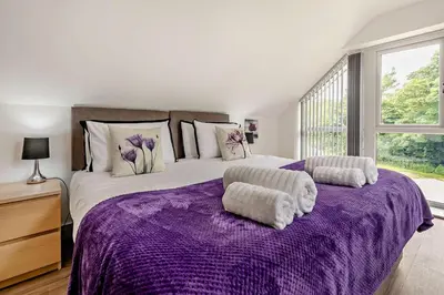 a bedroom with a purple bed with two ottomans at 4 Bed in Retorrick Mill oc-p28898 in Saint Mawgan