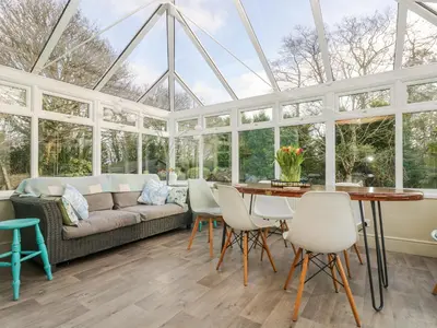 a conservatory with a couch and a table and chairs at Lower Gadles in Penryn