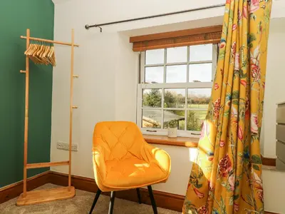 an orange chair in a room with a window at Lower Gadles in Penryn
