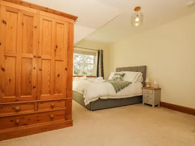 a bedroom with a bed and a large wooden cabinet at Lower Gadles in Penryn