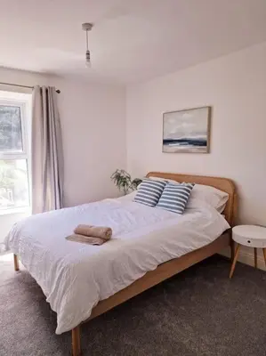 a bedroom with a large bed with two pillows at The Cove, Portreath in Portreath