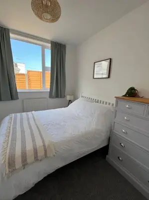 a bedroom with a bed and a dresser and a window at The Cove, Portreath in Portreath
