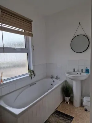 a white bathroom with a tub and a sink at The Cove, Portreath in Portreath