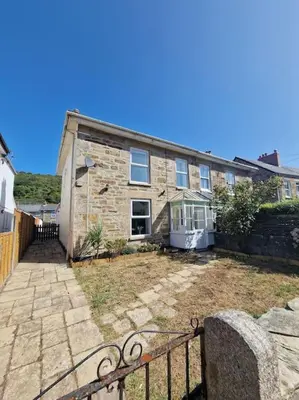 an old stone house with a fence in front of it at The Cove, Portreath in Portreath