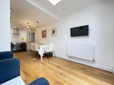 a living room with a table and chairs and a tv at 2 Meadow Villas in St Ives