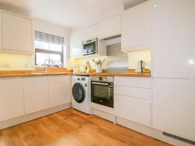 a kitchen with white cabinets and a washing machine at The Beach Hut in Newquay