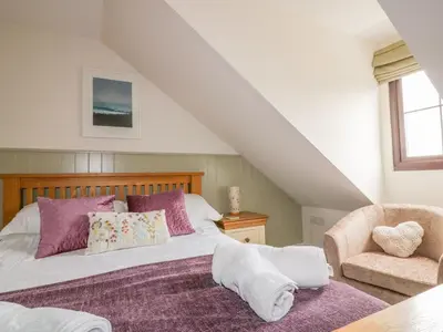 a bedroom with a bed and a chair at The Beach Hut in Newquay