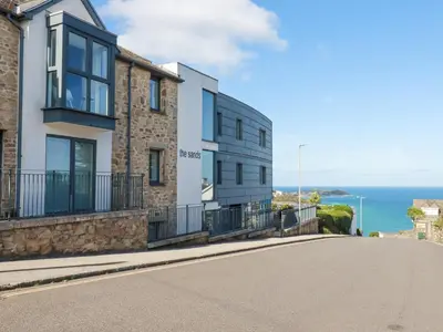 a house on a street with the ocean in the background at The Trick in St Ives
