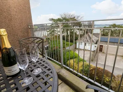 a table with two wine glasses on a balcony at Fal View in Falmouth