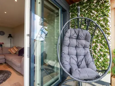a chair sitting on a porch next to a window at Fistral Tide in Newquay