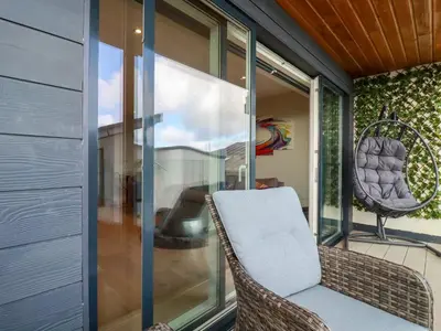 a balcony with a wicker chair and a window at Fistral Tide in Newquay