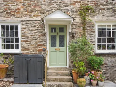 a stone house with a green door and two windows at Number One in Mevagissey
