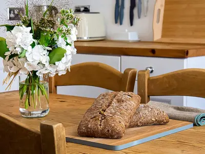 a wooden table with a vase of flowers and bread at Number One in Mevagissey