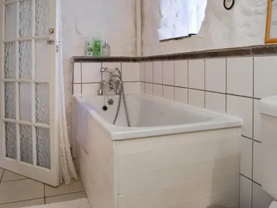 a white bath tub in a bathroom with a sink at Scrumpy Cottage in Bodmin