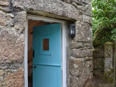 a door in a stone building with a blue door at Scrumpy Cottage in Bodmin