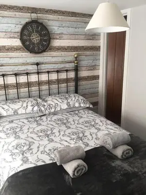 a bedroom with a bed with a clock on the wall at Guillemot Holiday Flat in Looe
