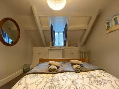 a bedroom with a large bed with towels on it at Guillemot Holiday Flat in Looe