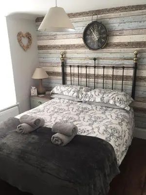 a bedroom with a bed with a clock on the wall at Guillemot Holiday Flat in Looe