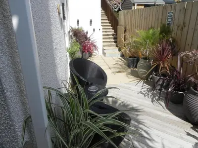 a patio with potted plants and a black chair at Gunnado in St Austell