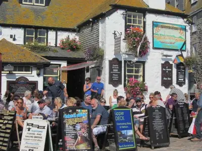 a group of people sitting at tables in front of a building at Gunnado in St Austell