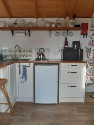 a kitchen with white cabinets and a white refrigerator at The Shepherd Hut in Carleen