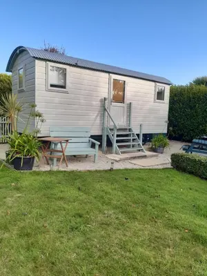 a tiny house with a picnic table and a bench at The Shepherd Hut in Carleen