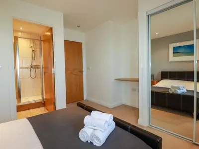 a hotel room with a bed and a shower and towels at Apartment 3 in Newquay
