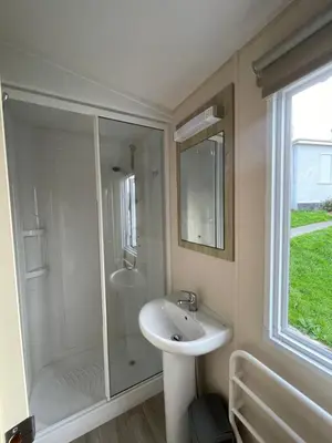 a white bathroom with a sink and a shower at Newquay Bay Holiday Resort Caravan 73 in Porth