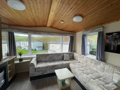 a living room with a couch and windows at Newquay Bay Holiday Resort Caravan 73 in Porth