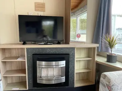 a living room with a fireplace and a tv at Newquay Bay Holiday Resort Caravan 73 in Porth