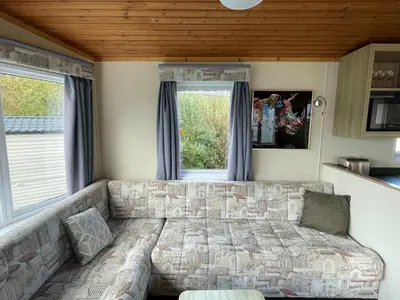 a living room with a couch in front of a window at Newquay Bay Holiday Resort Caravan 73 in Porth